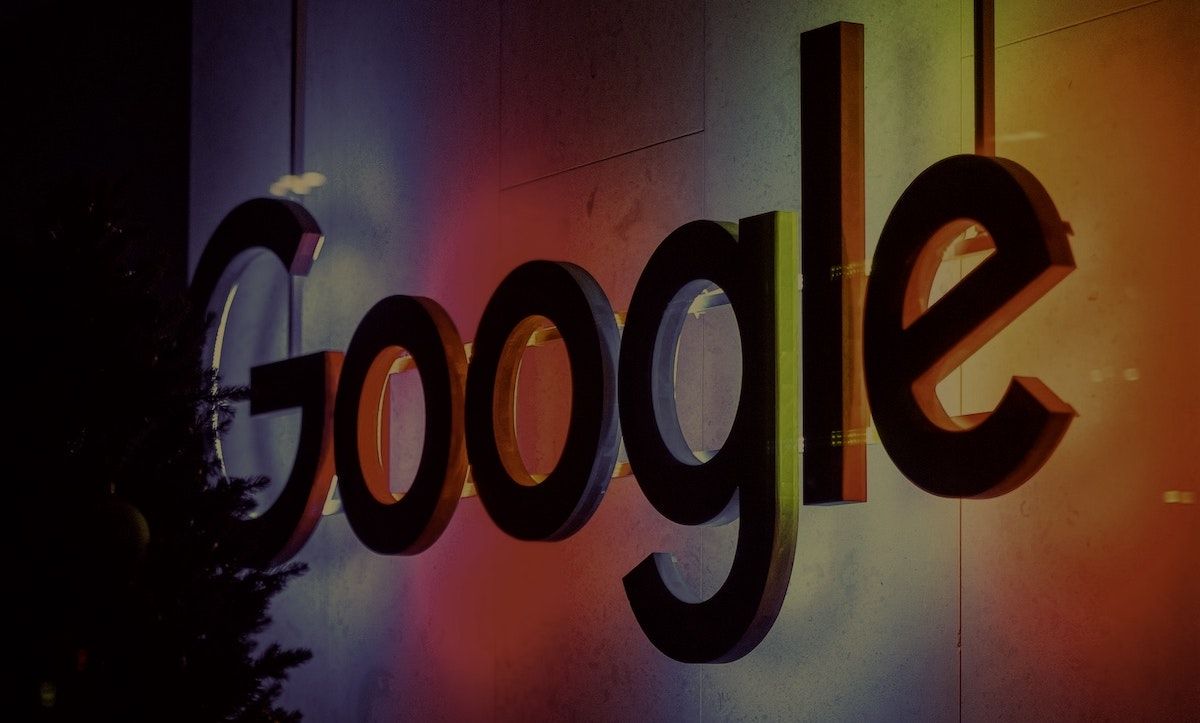 A sign of the google logo backlit by orange and pink neon