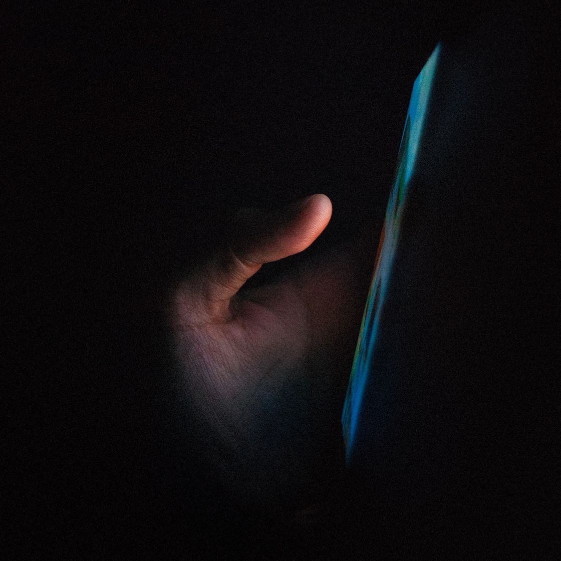 A hand holding a phone with a web app on the screen glows in the dark