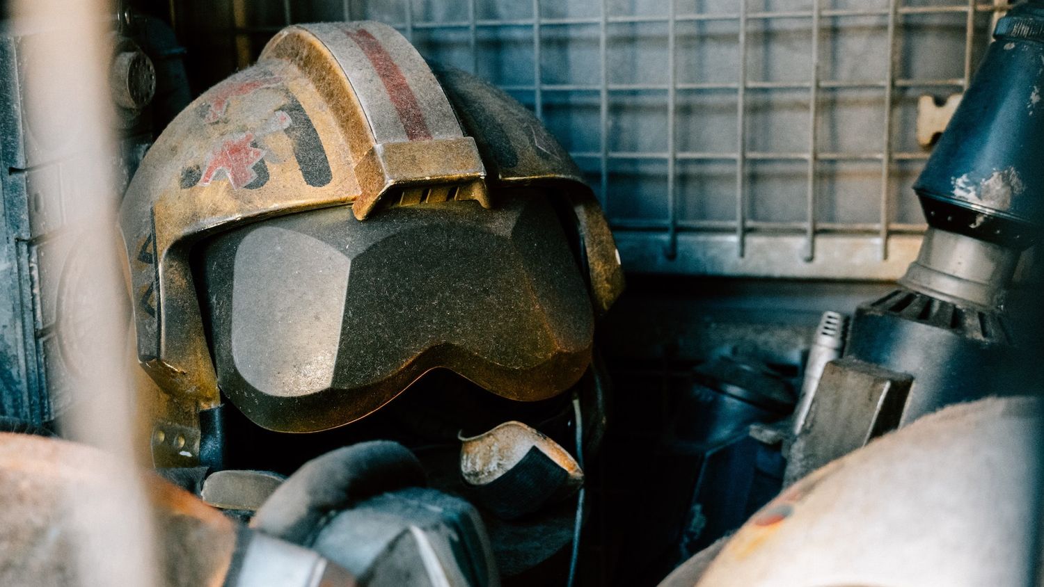 a sci-fi pilot sits in a cockpit, his head covered by futuristic googles and battle scarred helmet