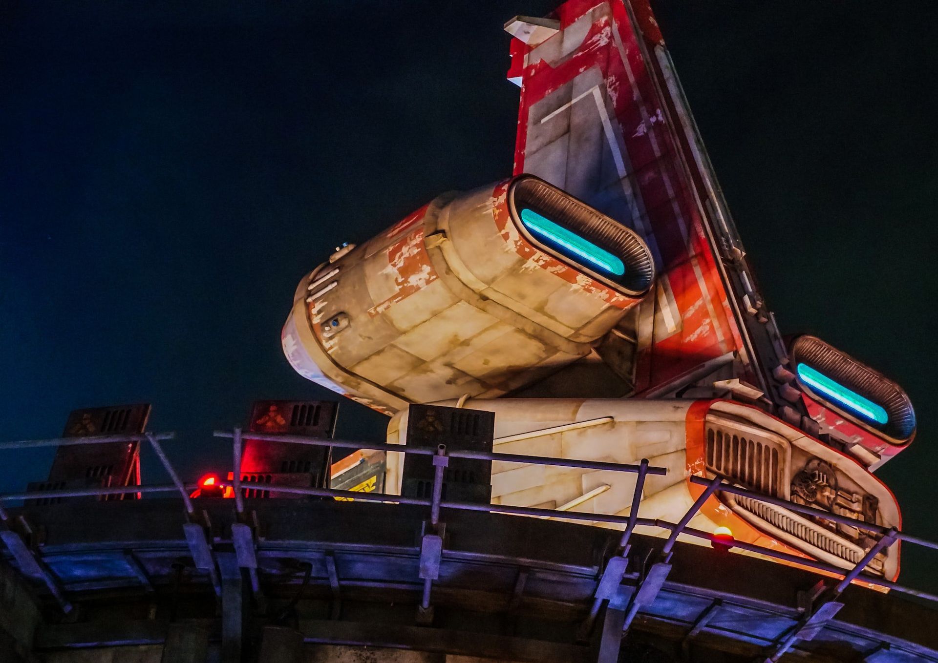 a futuristic spacecraft sits on a landing pad at night, guided by a glowing orange light